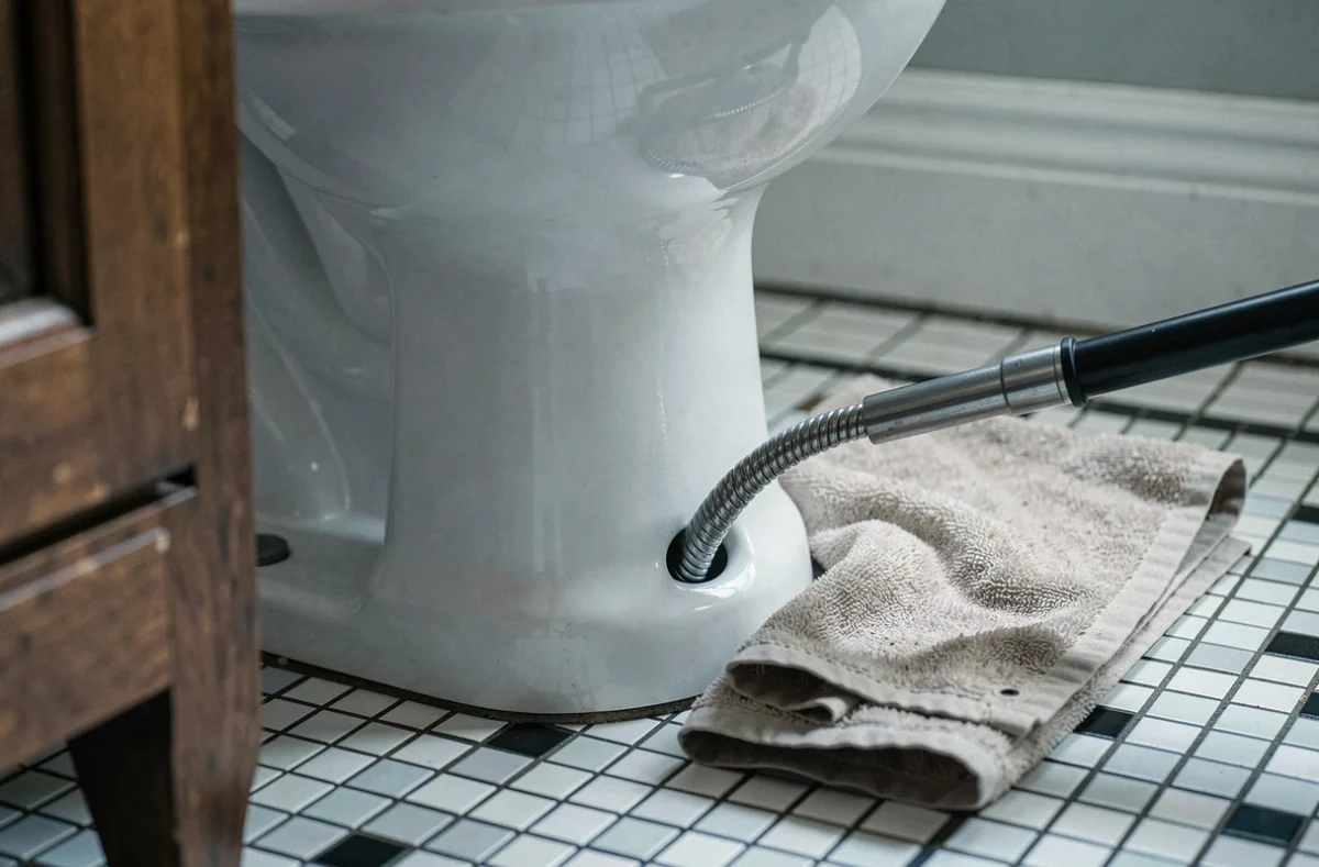 Furet de plomberie inséré dans des toilettes bouchées, vue rapprochée sur carrelage vintage