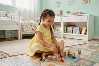 Jeune fille jouant sur un sol en linoléum coloré dans une chambre d'enfant décorée en tons pastel